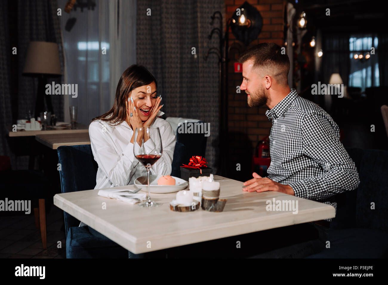 Portrait de jeune femme heureux et surpris de recevoir des présents de petit ami alors qu'il était assis dans le café Banque D'Images