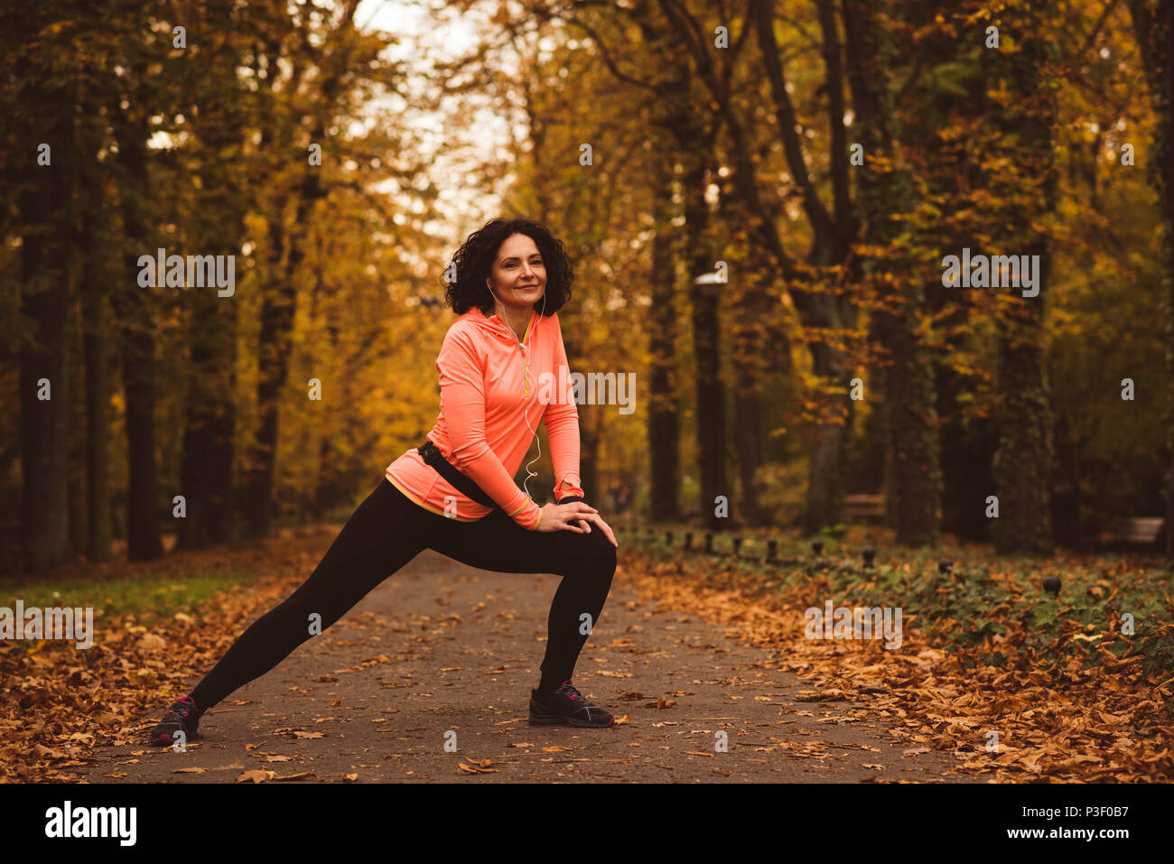 Woman performing exercice s'étendant dans la forêt Banque D'Images