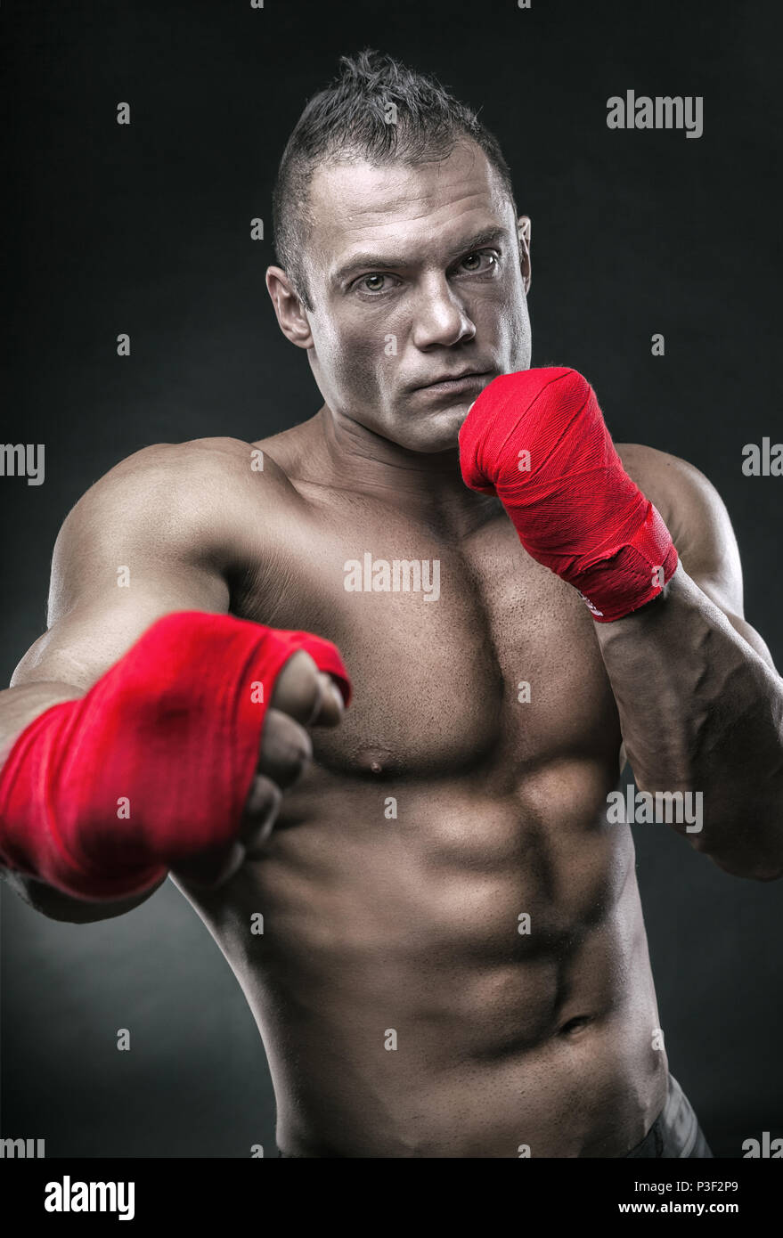 Close-up d'une main du boxeur prêt pour un combat. Les mains fortes et les poings serrés dans les sangles rouges Banque D'Images