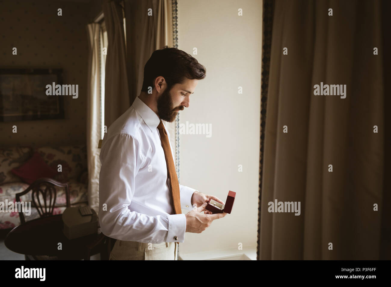 Groom holding un anneau de mariage près de la fenêtre Banque D'Images