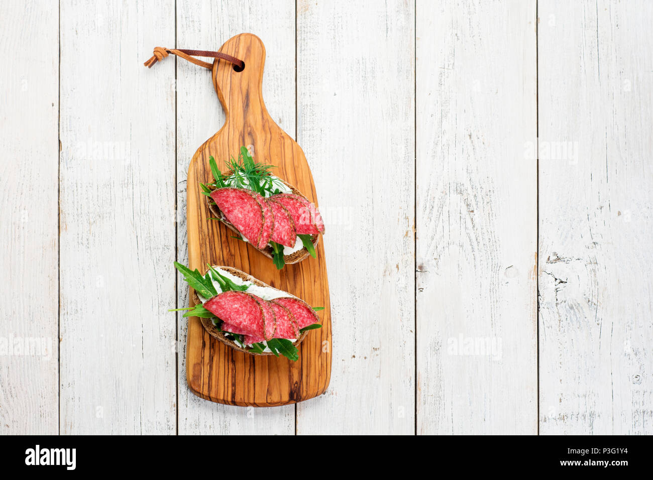 Savoureux hors-d'émincé de salami épicé sur du pain avec du fromage et des herbes sur une planche à découper, copy space Banque D'Images