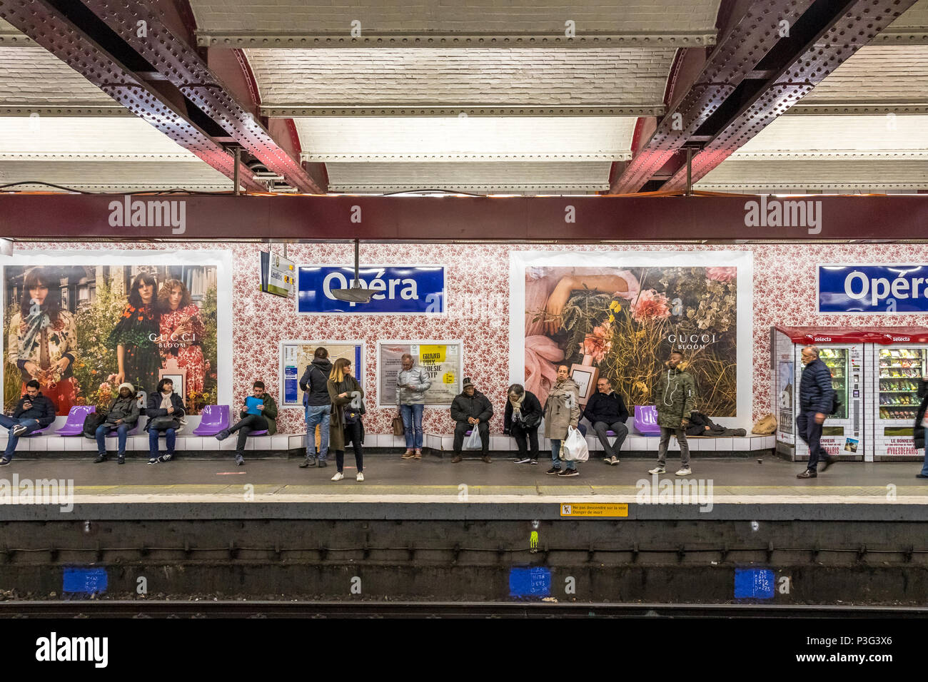 Personnes en attente d'un train à la station de métro Opéra à Paris .La station des murs ont été recouvert de papier peint fleuri pour une promotion Bloom Gucci Banque D'Images