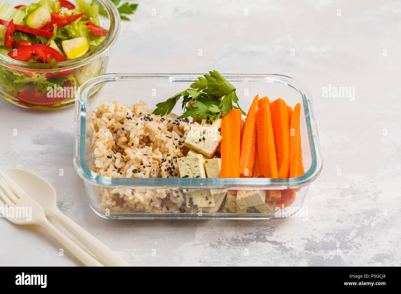 Préparation des repas sains avec des conteneurs de riz brun, tofu et légumes frais Salades tourné avec copie espace. La nourriture végétalienne saine concept. Banque D'Images