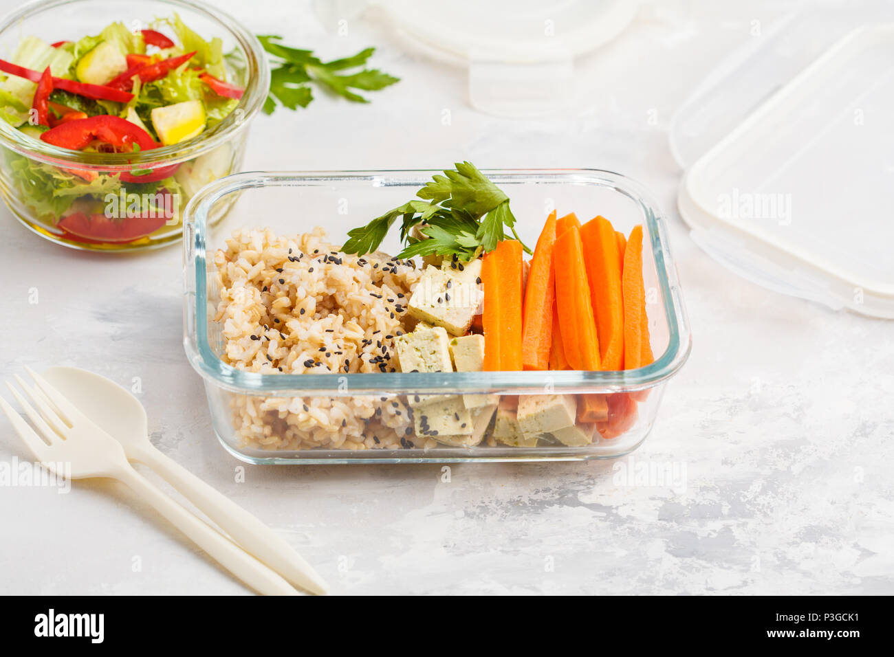 Préparation des repas sains avec des conteneurs de riz brun, tofu et légumes frais Salades tourné avec copie espace. La nourriture végétalienne saine concept. Banque D'Images