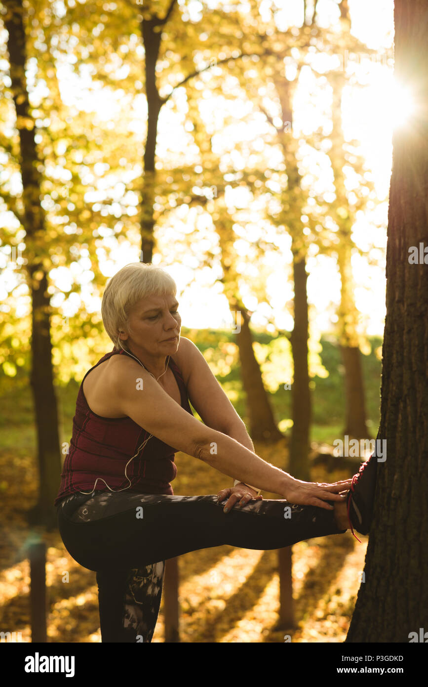 Senior woman performing exercice s'étendant dans le parc Banque D'Images