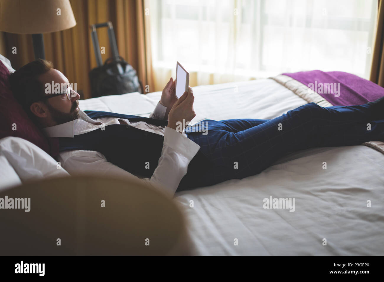 Businessman using digital tablet in bedroom Banque D'Images