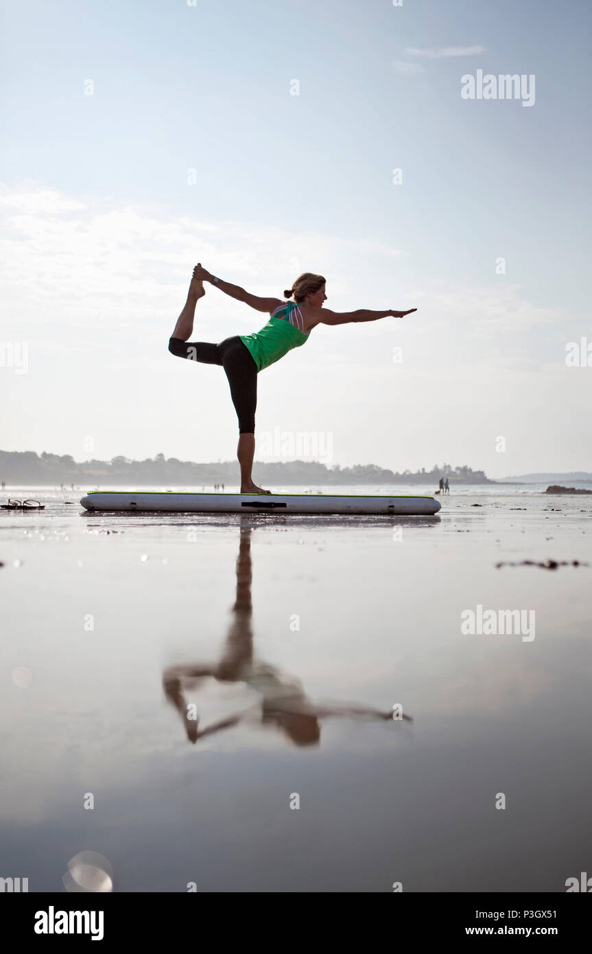 Une femme pratique le yoga à une plage dans le sud du Maine. Banque D'Images