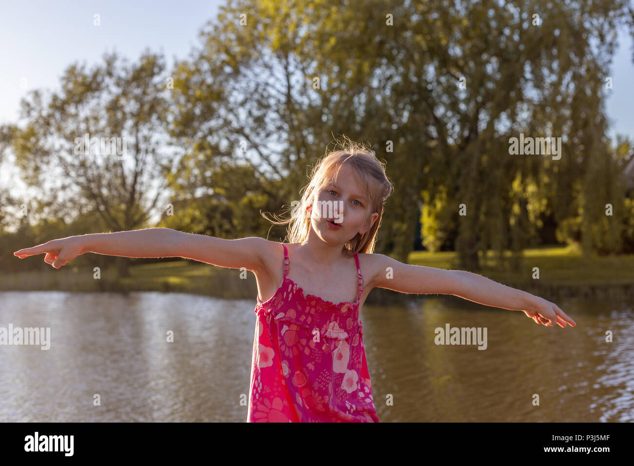 Une fillette de 7 ans s'étend ses bras et fait un avion en vol Banque D'Images
