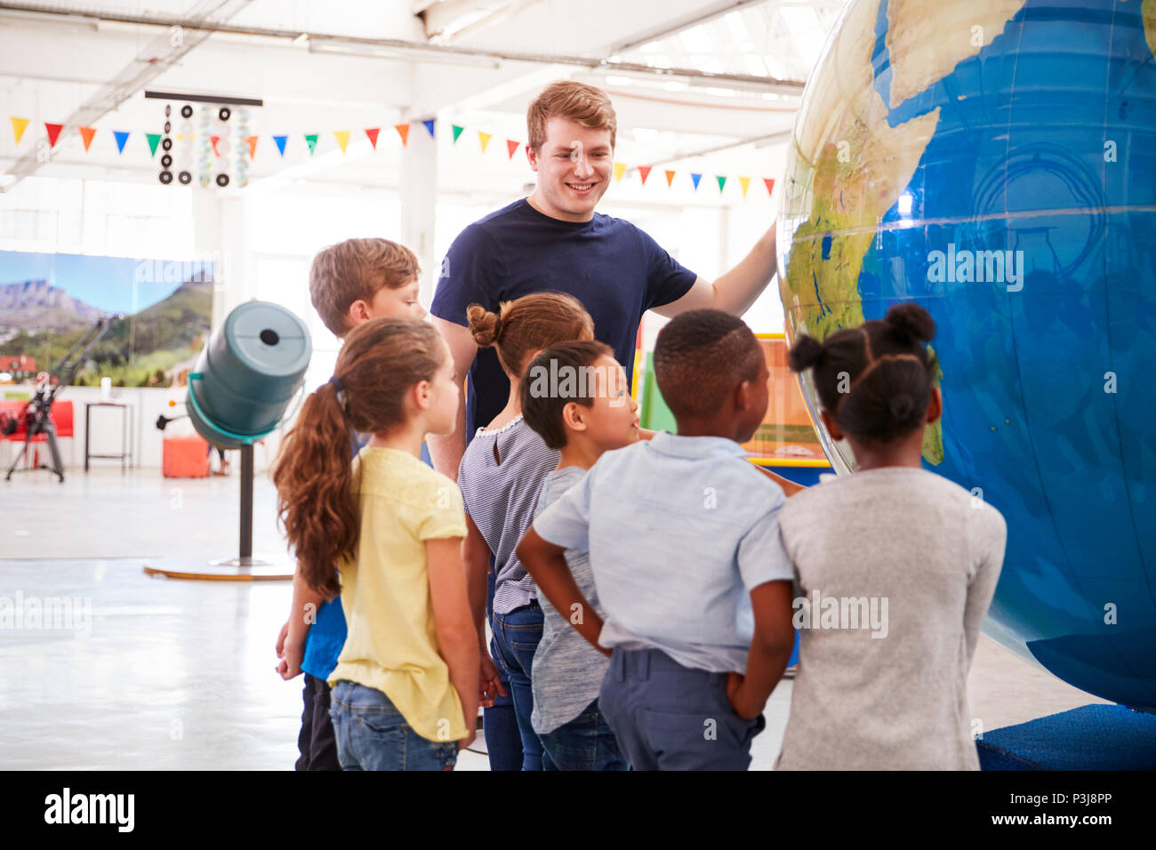 Les enfants de l'école à la recherche d'un globe géant dans un centre des sciences Banque D'Images