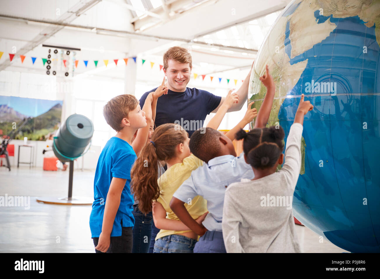 Les enfants de l'école montrant un globe géant dans un centre des sciences Banque D'Images