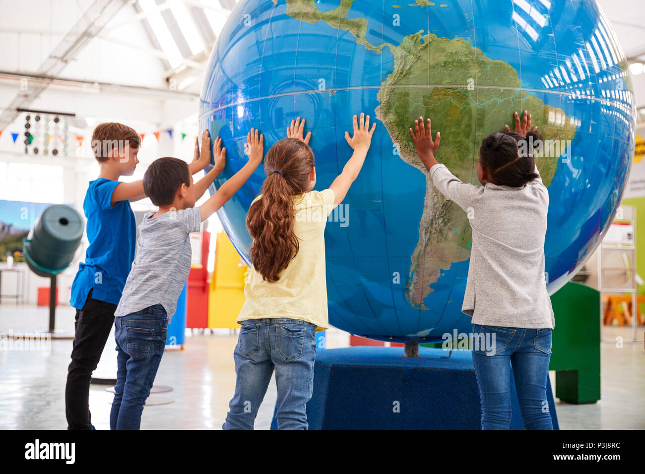 Groupe d'élèves de l'école de holding globe géant dans un centre des sciences Banque D'Images