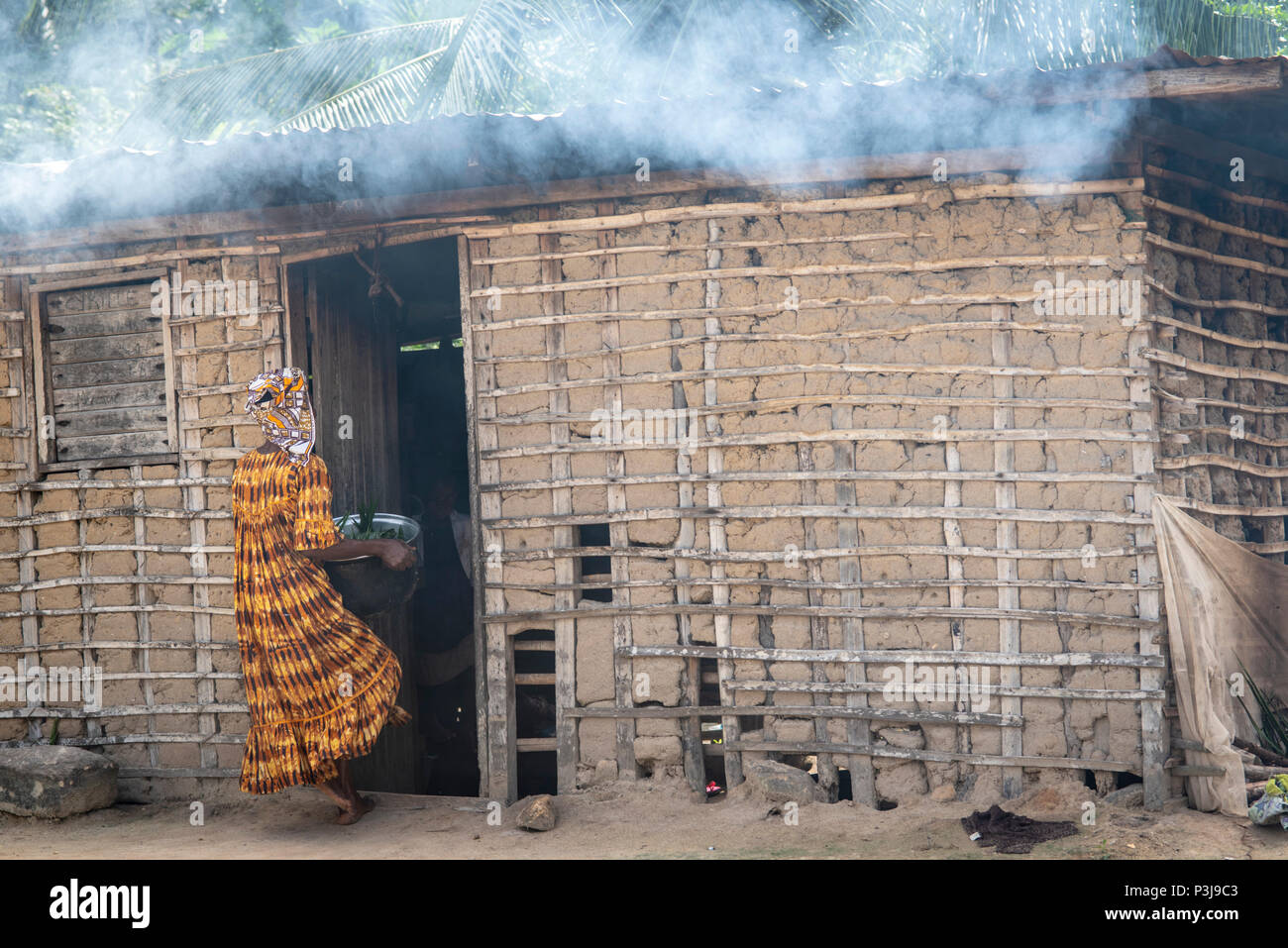 Maison pygmée et la femme à l'orange et stripe vêtements traditionnels, Bagyliem, Cameroun Banque D'Images