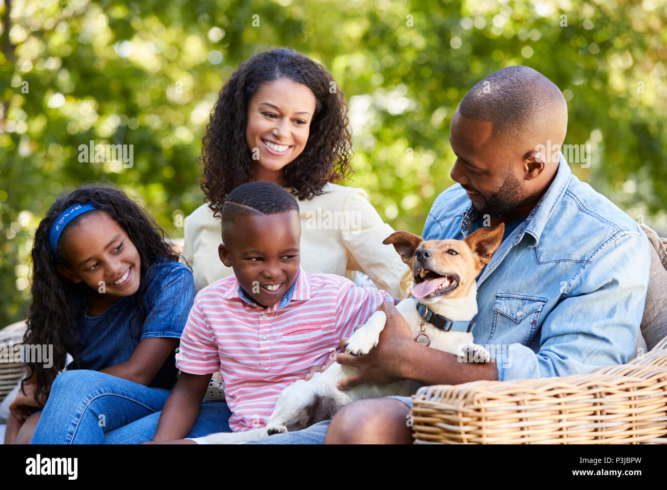 Les parents et deux enfants assis avec le chien dans le jardin Banque D'Images