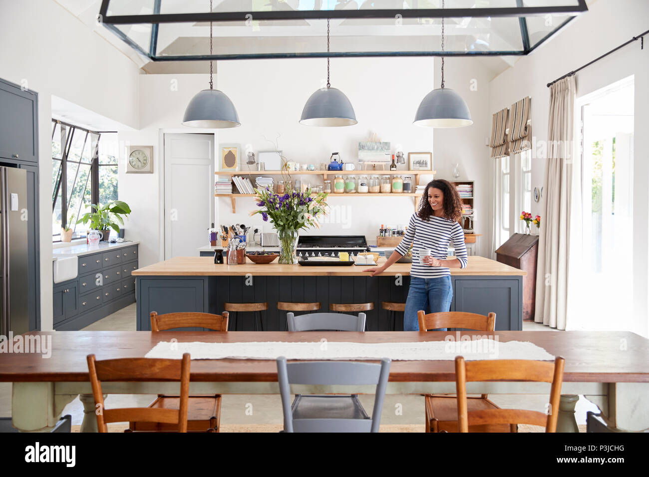 Mixed Race woman leaning on kitchen island en plan ouvert accueil Banque D'Images