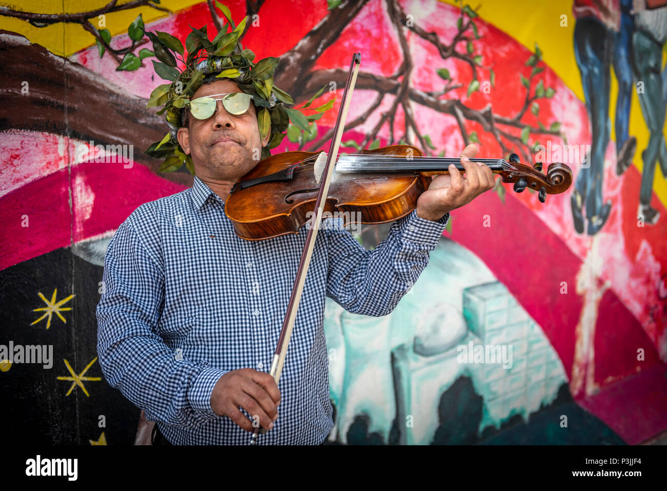 Un musicien ambulant divertit les touristes sur le site du Mur de Berlin, en ex-Allemagne de l'Est. Banque D'Images