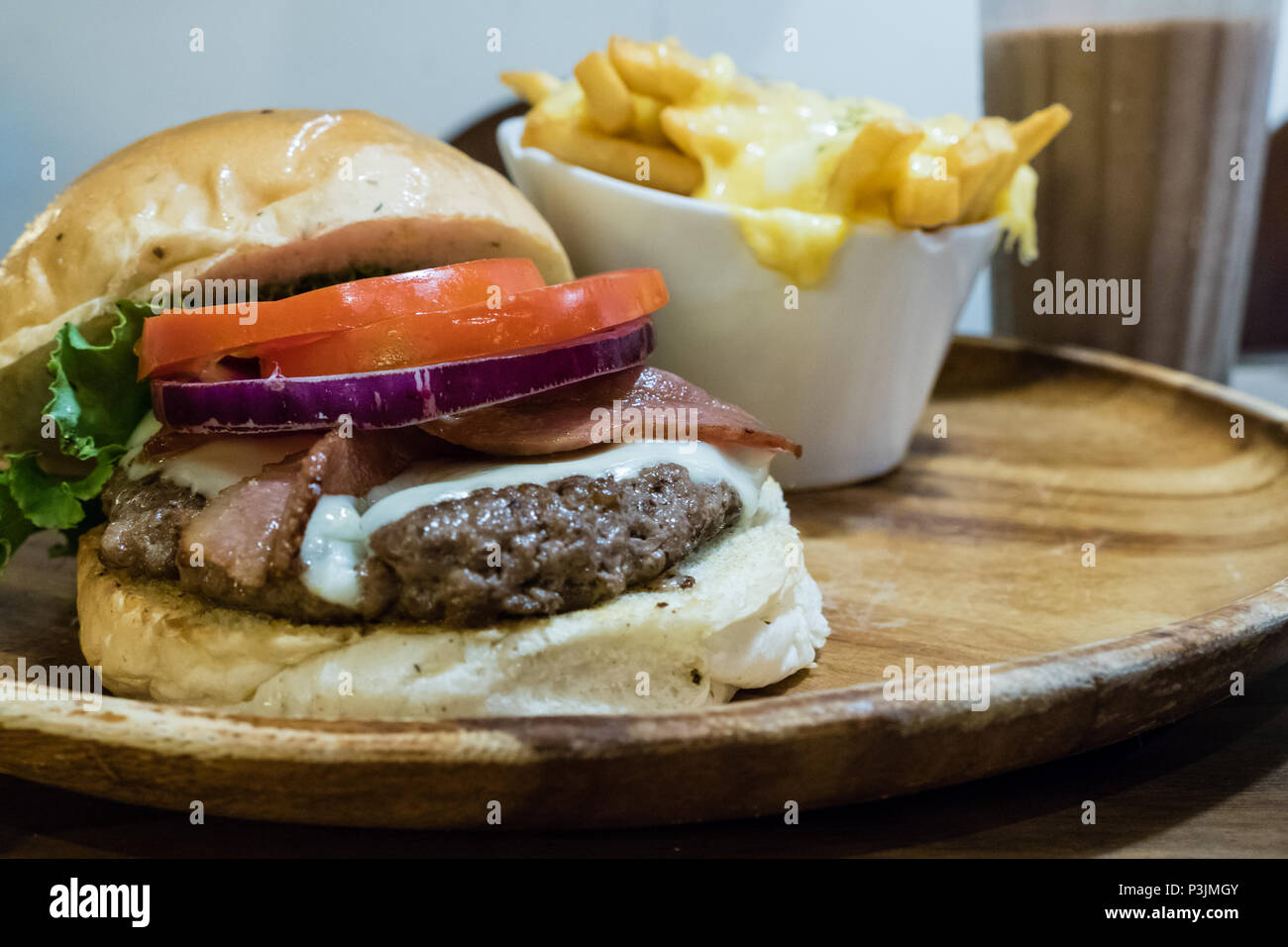 Bacon burger avec frites fromage sur plateau en bois Banque D'Images