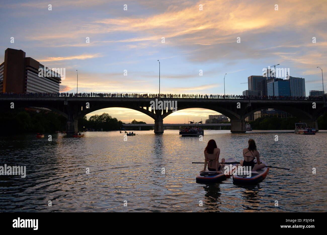 Deux filles paddle dans la soirée pour regarder la le Congrès ave les chauves-souris sortent sur le lac Coccinelle à Austin, Texas. Banque D'Images