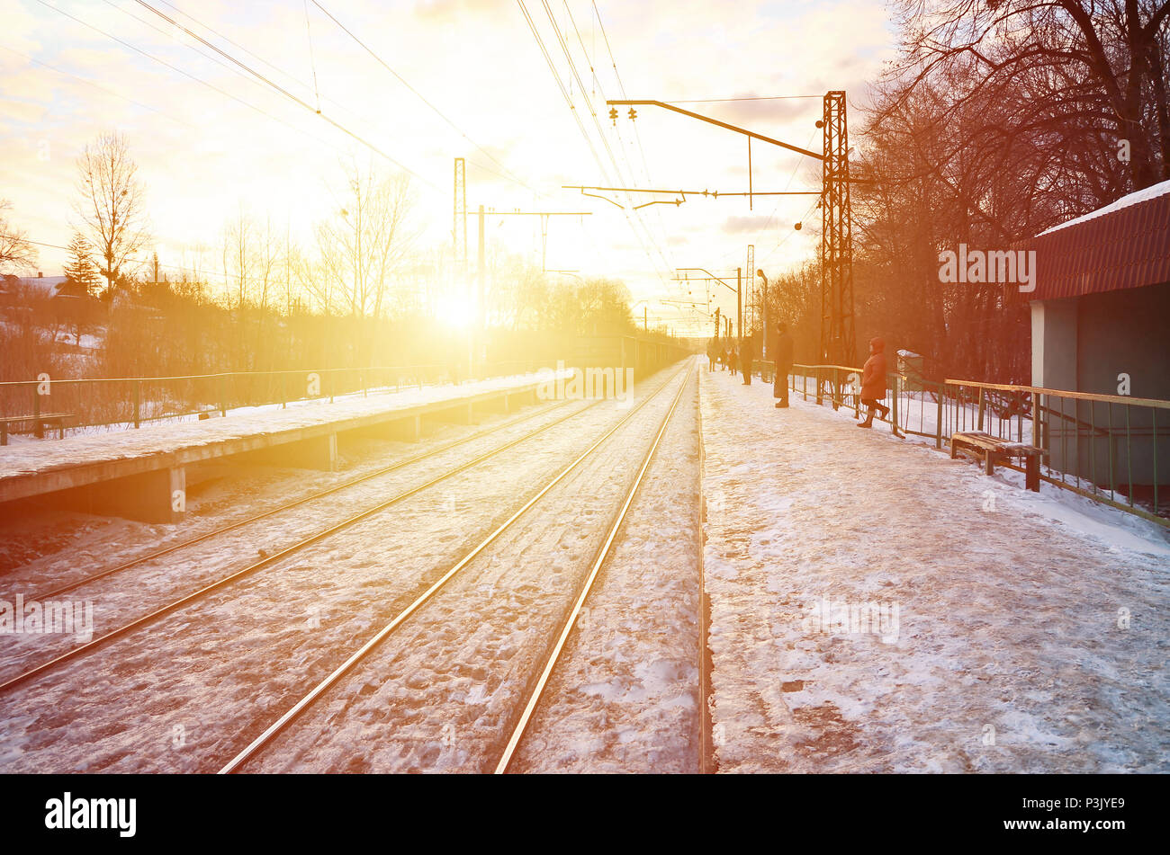 Photo de lumineux et beau coucher de soleil sur un ciel nuageux en saison froide d'hiver. Voie de chemin de fer avec des plates-formes pour les trains en attente de transmission de puissance et de lin Banque D'Images