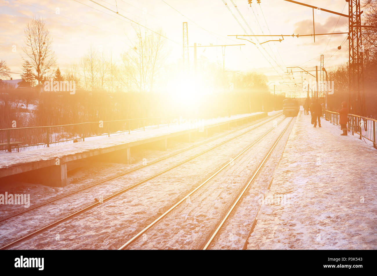 Photo de lumineux et beau coucher de soleil sur un ciel nuageux en saison froide d'hiver. Voie de chemin de fer avec des plates-formes pour les trains en attente de transmission de puissance et de lin Banque D'Images