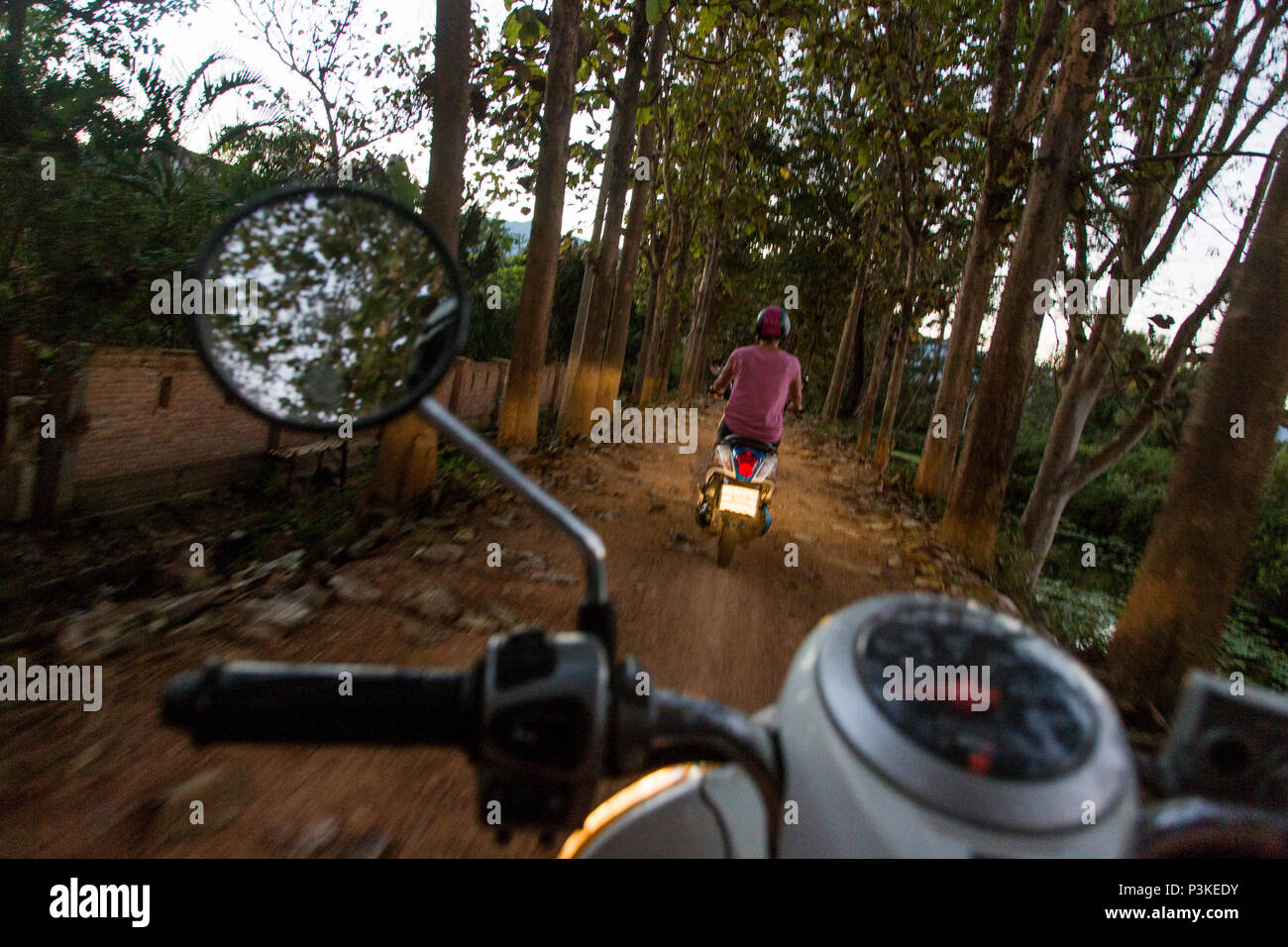 Woman riding scooter sur route de terre, PAI, Mae Hong Son, Thaïlande bientôt Banque D'Images