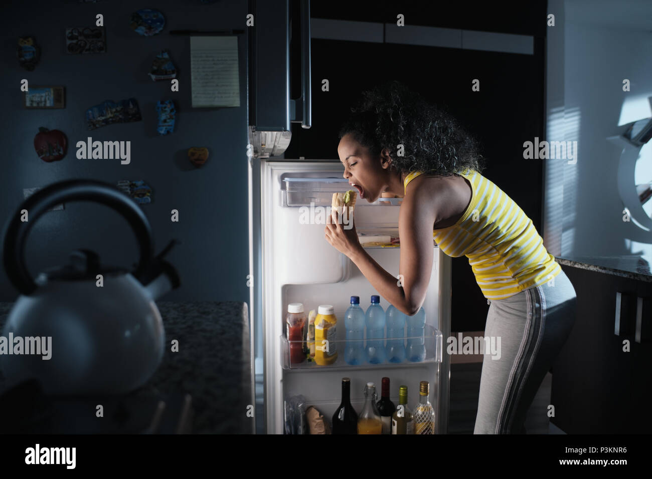 Femme noire à la recherche dans un réfrigérateur pour casse-croûte de minuit Banque D'Images