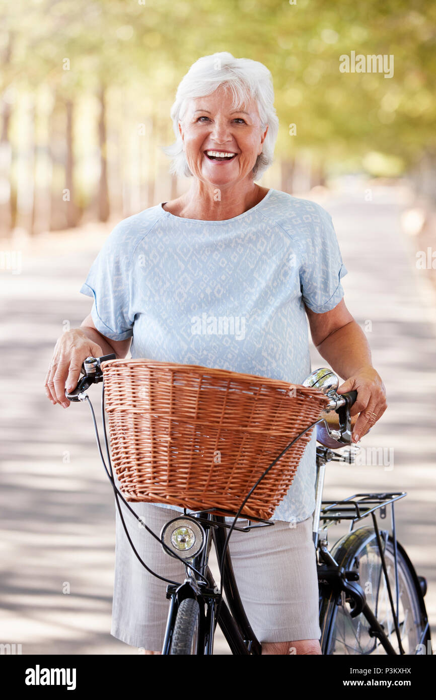 Portrait Of Smiling Senior Woman sitting on Country Road Banque D'Images