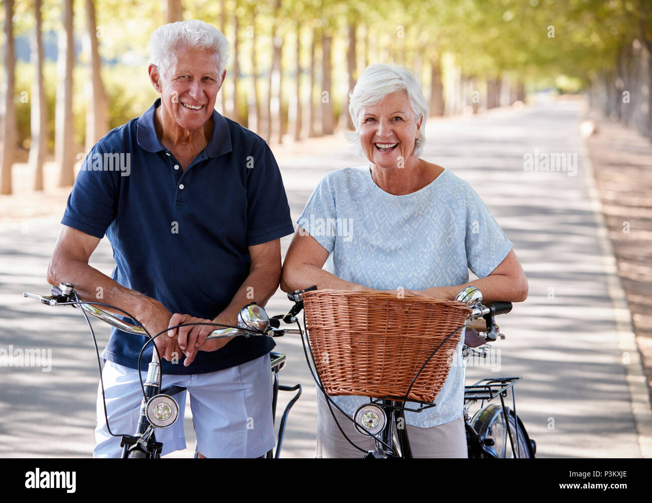 Portrait Of Smiling Senior Couple Cycling On Country Road Banque D'Images