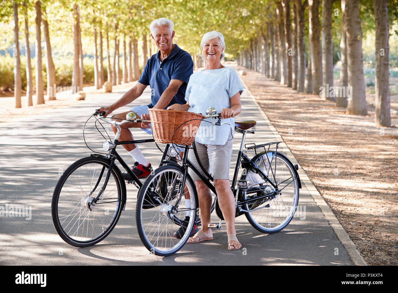 Portrait Of Smiling Senior Couple Cycling On Country Road Banque D'Images