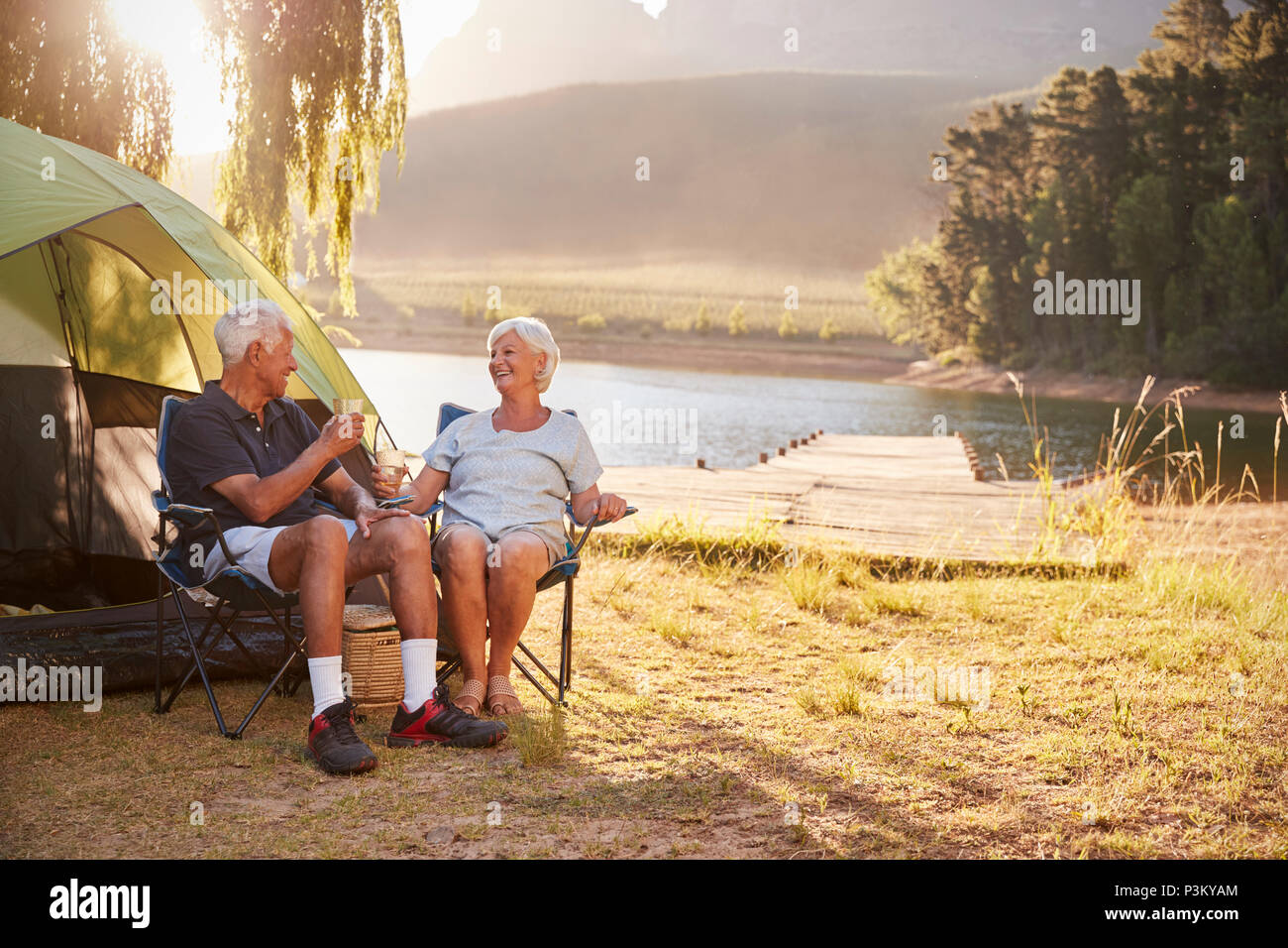 Senior Couple Enjoying Camping Locations par le lac faire un toast Banque D'Images