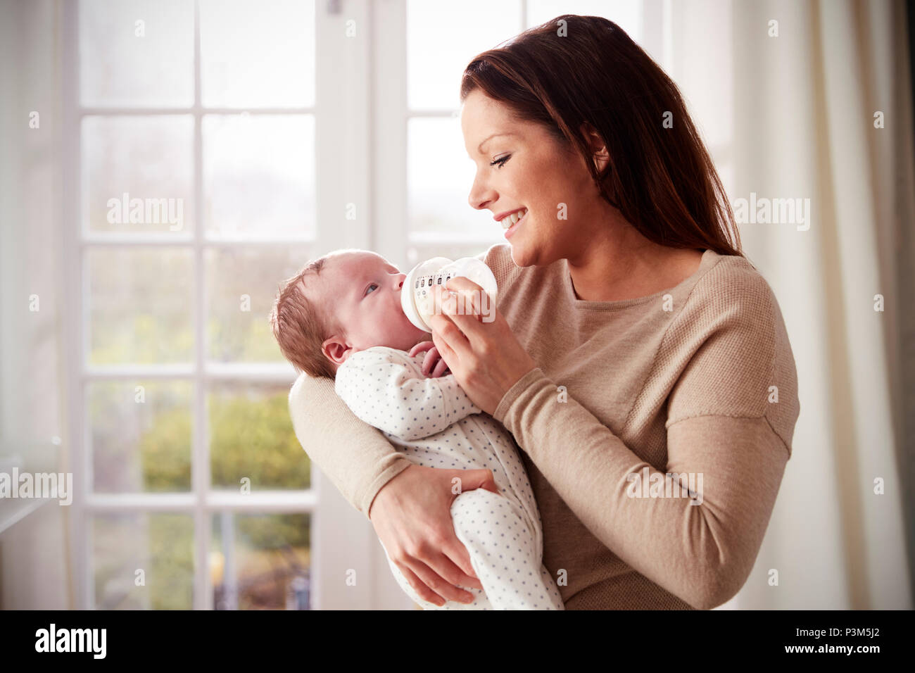 L'alimentation de la mère bébé nouveau-né à partir de la bouteille à la maison Banque D'Images