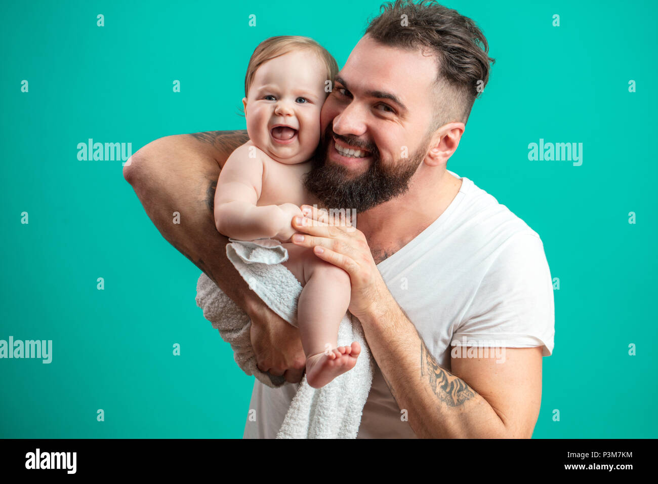 Son père ludique smiling infant child sur cou sur fond bleu Banque D'Images