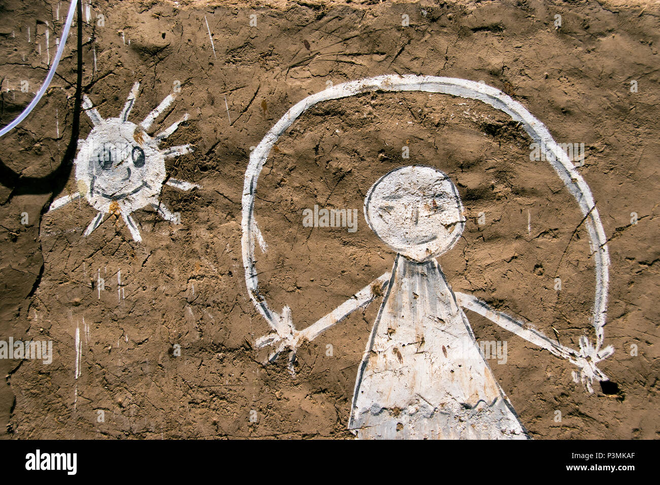 Une image peinte de la corde à sauter et le soleil sur un mur de boue d'une maison nubienne sur l'île Eléphantine à Assouan, Egypte. Banque D'Images