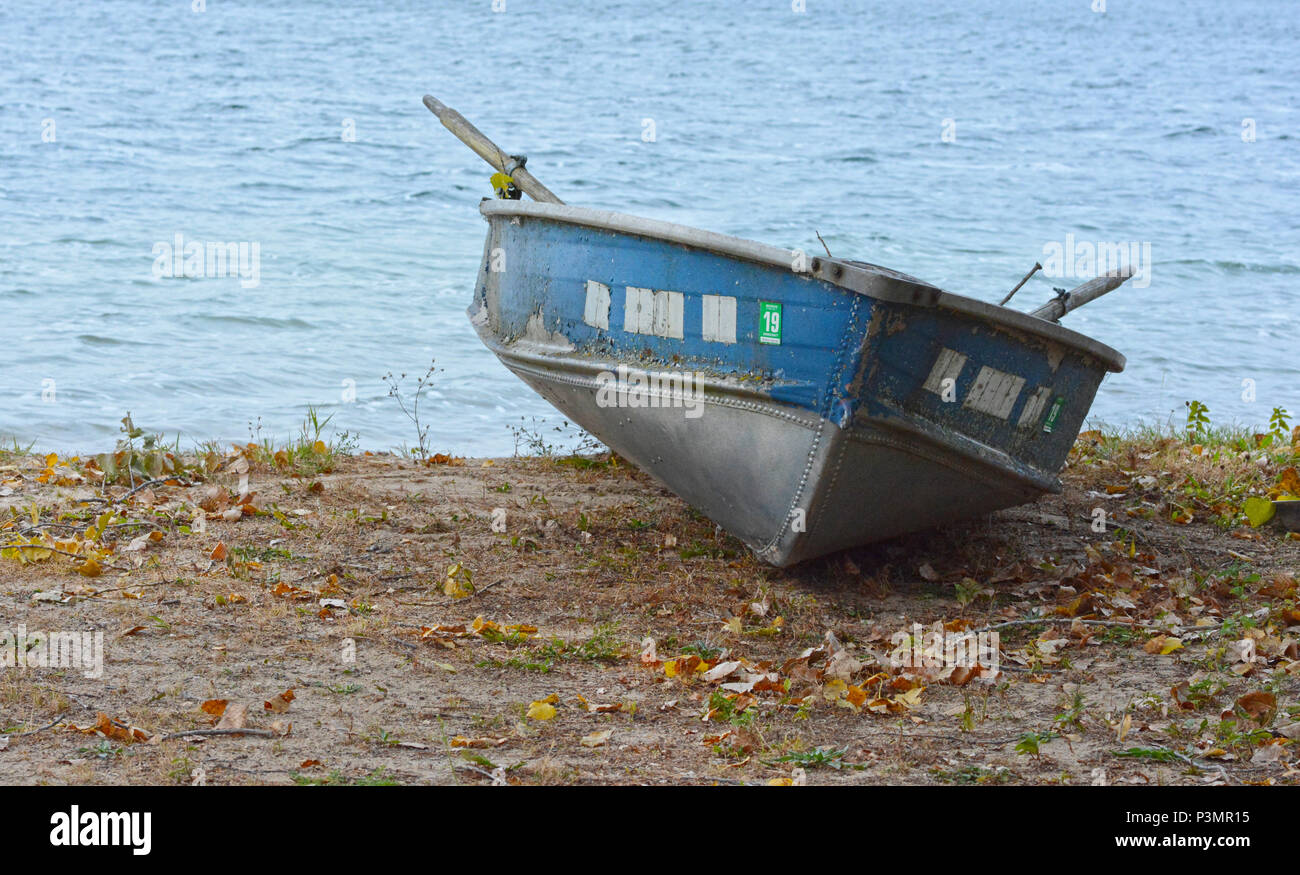Une barque bleue est tiré sur le rivage à côté d'un plan d'eau. Banque D'Images