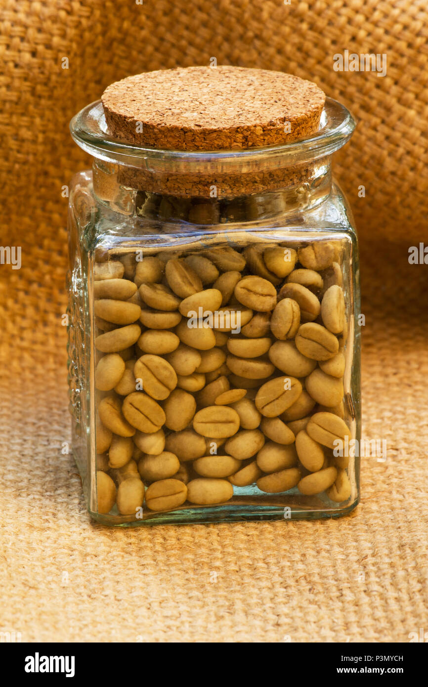 Les grains de café vert dans un pot sur le jute Banque D'Images