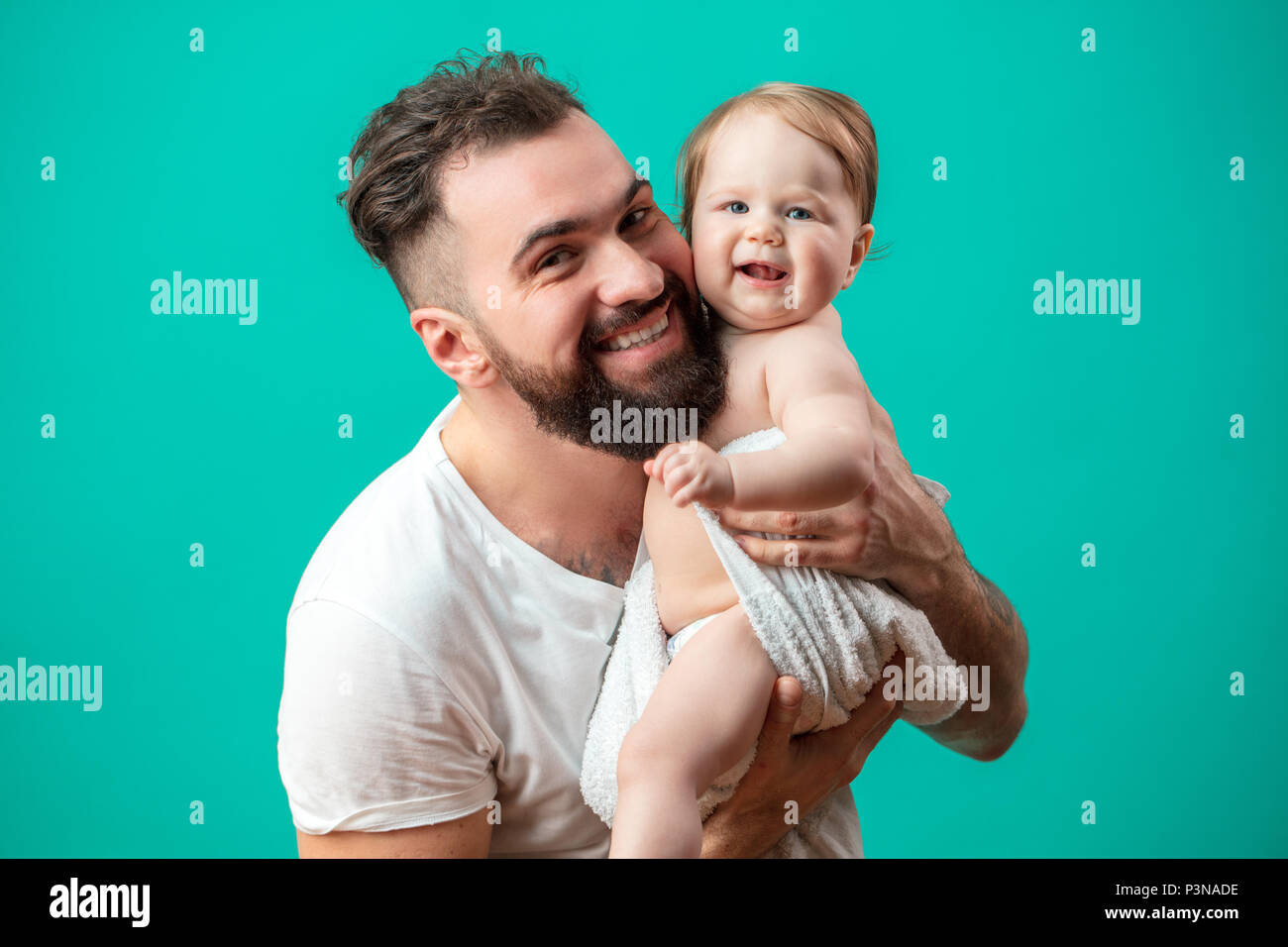 Son père ludique smiling infant child sur cou sur fond bleu Banque D'Images