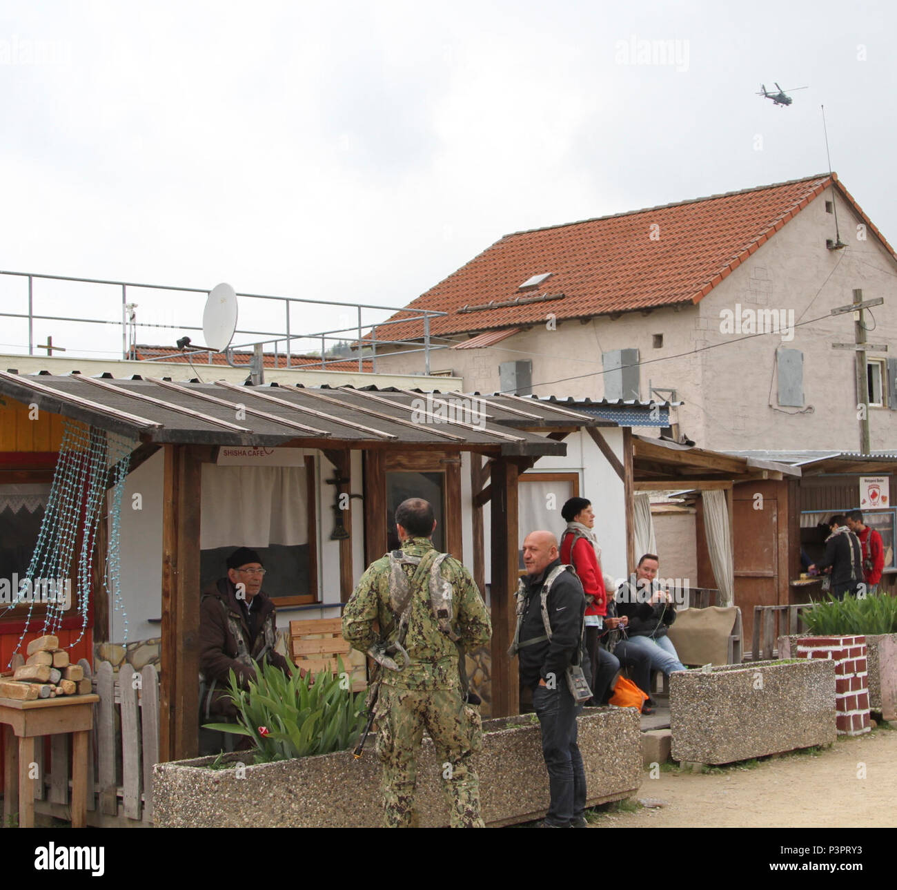 Un commandant d'une unité d'opérations spéciales de la marine américaine s'engage avec un ancien dans un village simulé comme une armée américaine d'hélicoptères Apache AH-64D à partir de la 10e Brigade d'aviation de combat rond le périmètre lors de l'exercice de tuteur 17 Sabre au Centre de préparation interarmées multinationale à Hohenfels, Allemagne, le 7 mai 2017. Sortie 17 Sabre d'exercice est une Europe de l'armée américaine-dirigé exercice visant à évaluer l'état de préparation de l'Armée 2e régiment de cavalerie pour mener des opérations terrestres unifiée aux côtés de l'OTAN et de pays partenaires. Banque D'Images