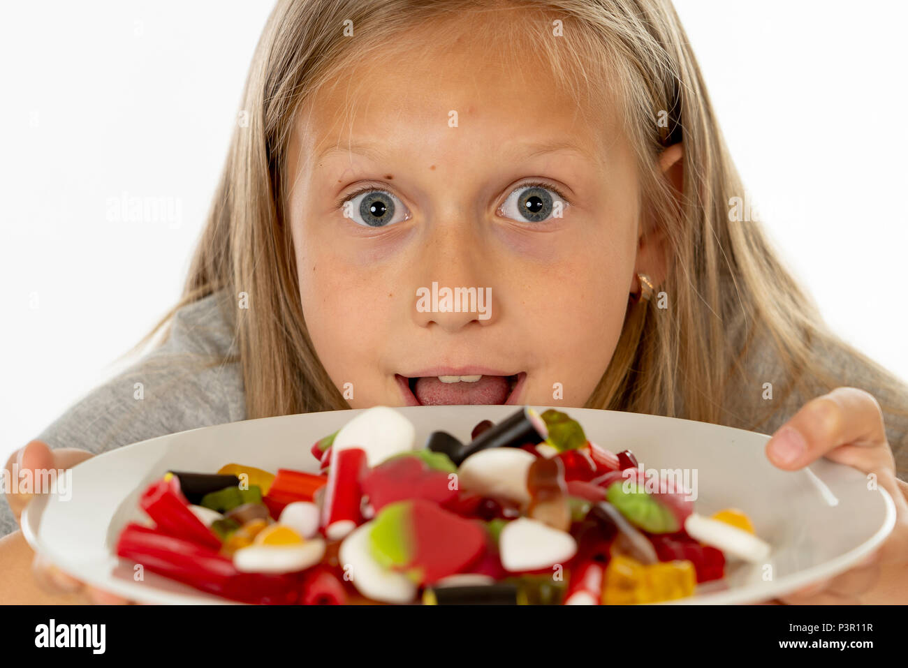 Funny happy girl avec la plaque de bonbons sucette lollies happy little girl eating big sugar candy lollies kid manger des sucreries. surpris enfant avec des bonbons. iso Banque D'Images