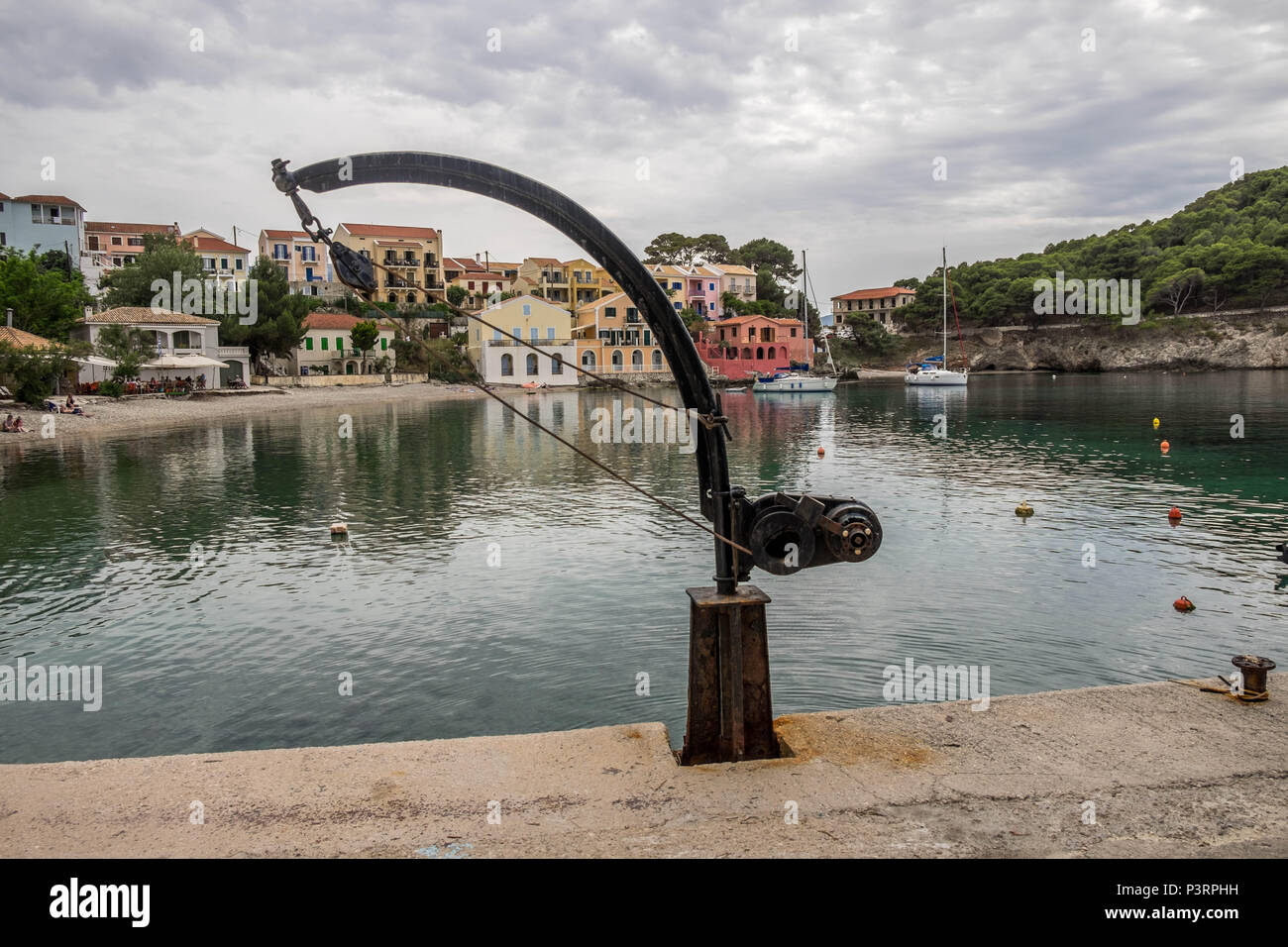 La plage d'Assos montrant de petites embarcations et la grue de levage de bateaux de l'eau. Banque D'Images