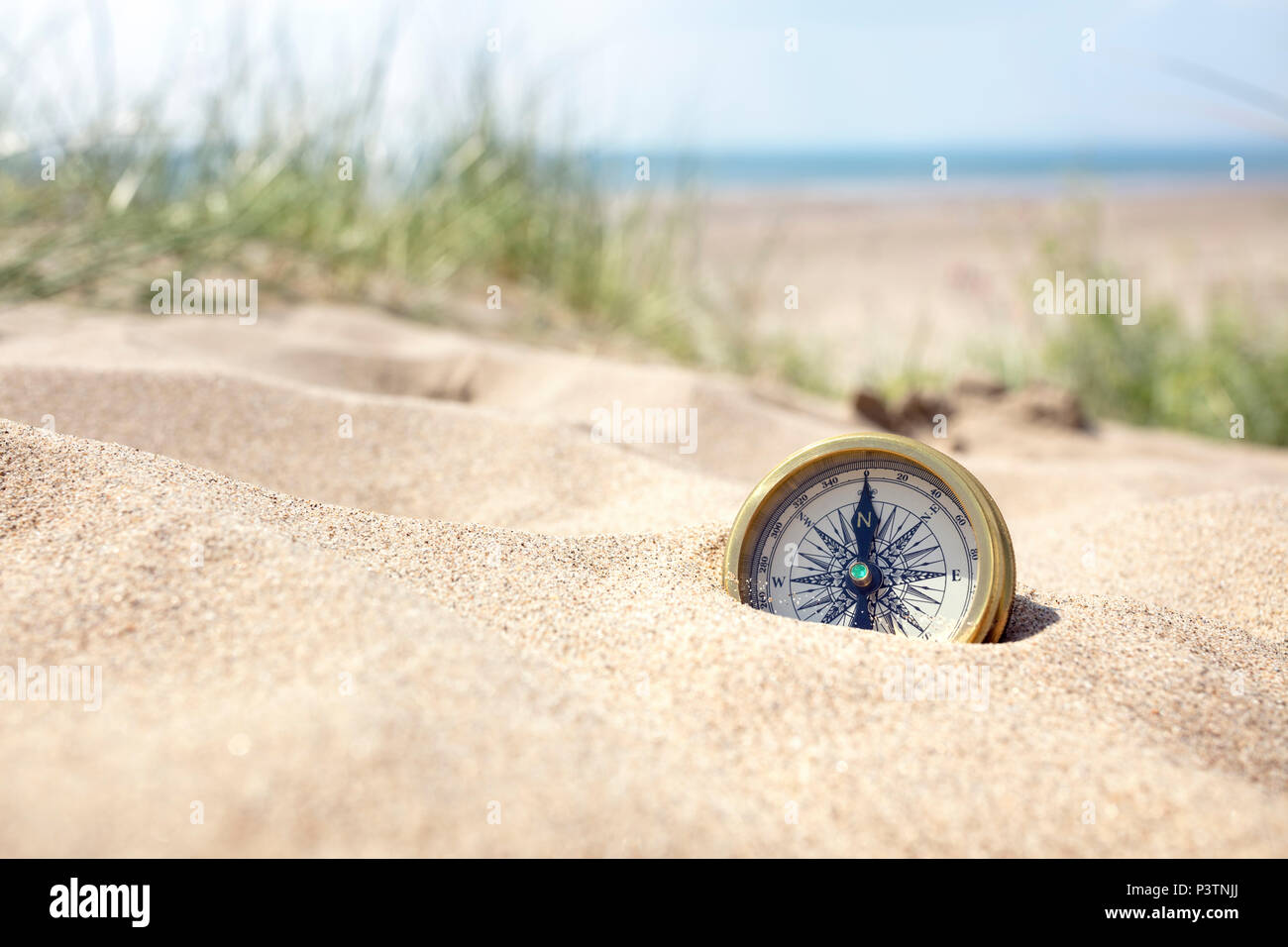 Boussole d'enterré dans le sable sur la plage pour la perte ou la direction concept Banque D'Images
