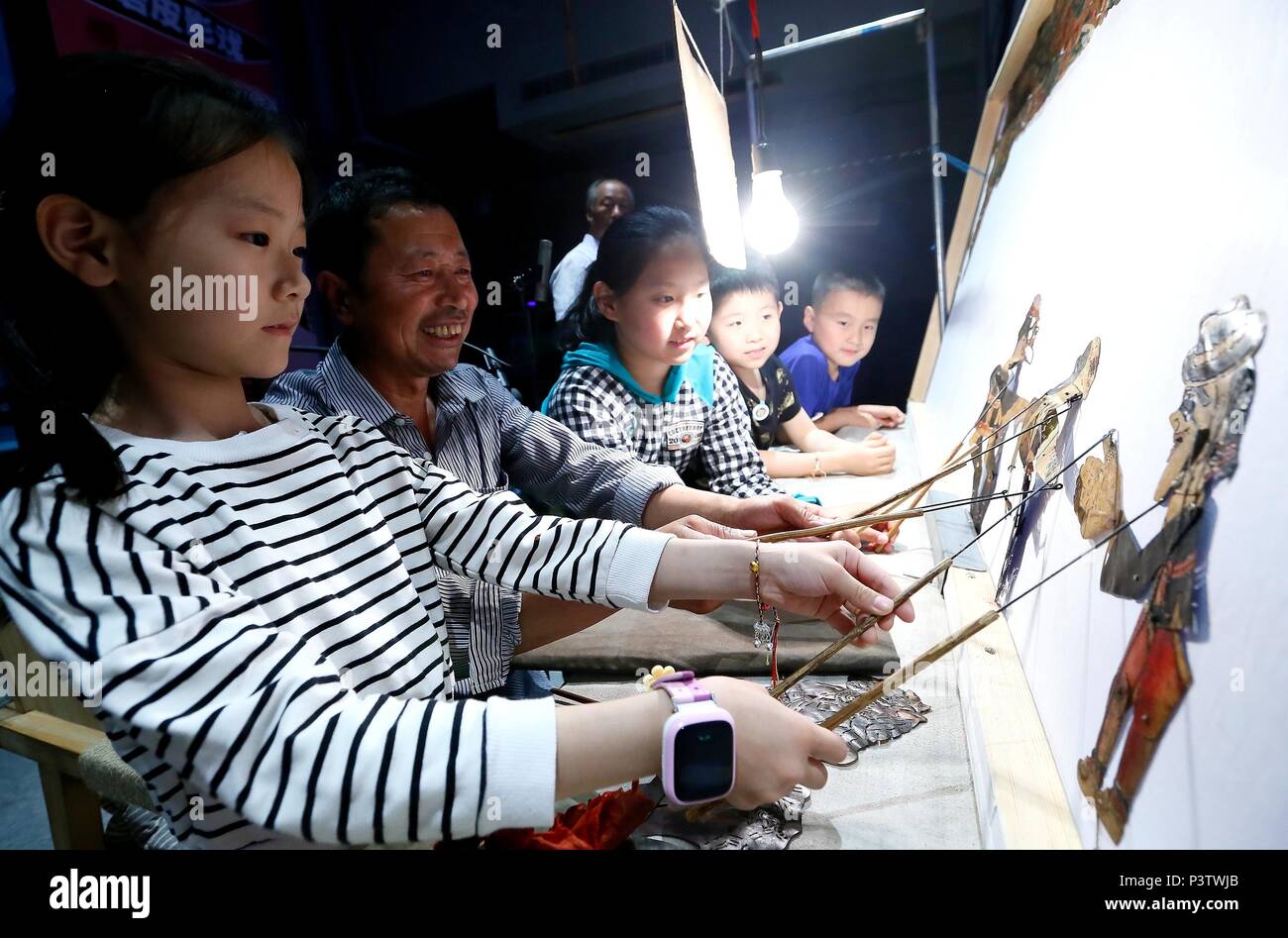 (180619) -- QINGDAO, 19 juin 2018 (Xinhua) -- Les élèves apprennent à effectuer avec des ombres chinoises sous la direction d'artistes folk dans l'ancienne ville de Chengyang à Qingdao, province de Shandong en Chine orientale, le 18 juin 2018. Artistes de Anshan, province de Liaoning ont organisé des spectacles de marionnettes d'ombres traditionnel pour les résidents locaux à Qingdao. (Xinhua/Liang Xiaopeng)(wsw) Banque D'Images