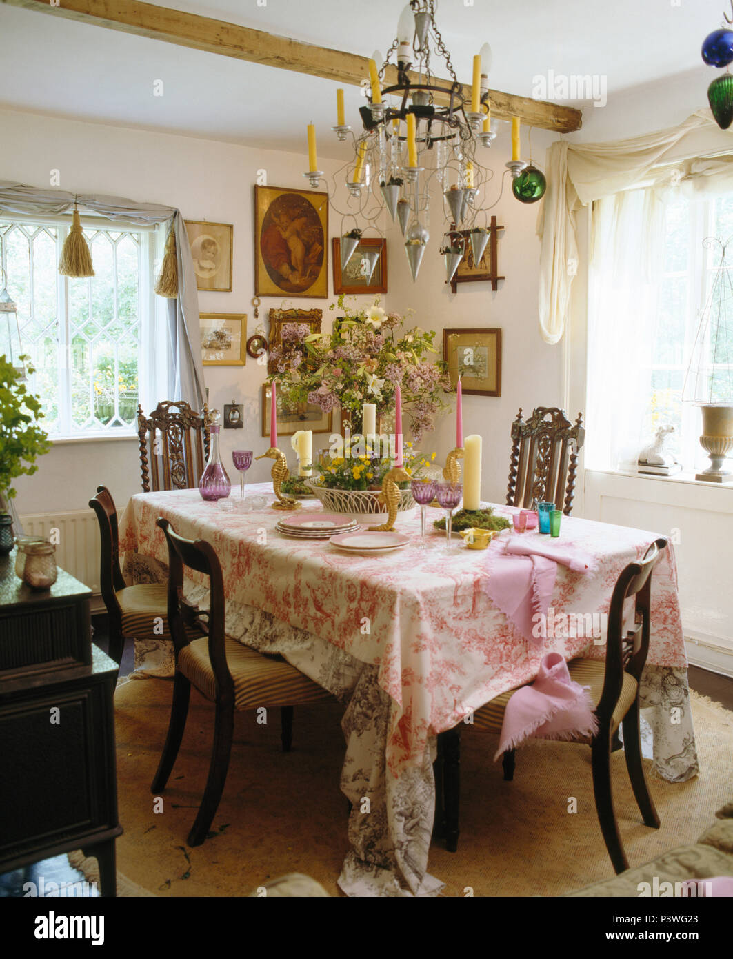 Chandelier bougie table avec toile rose-de-Jouy tissu dans pays salle à manger avec chaises anciennes Banque D'Images