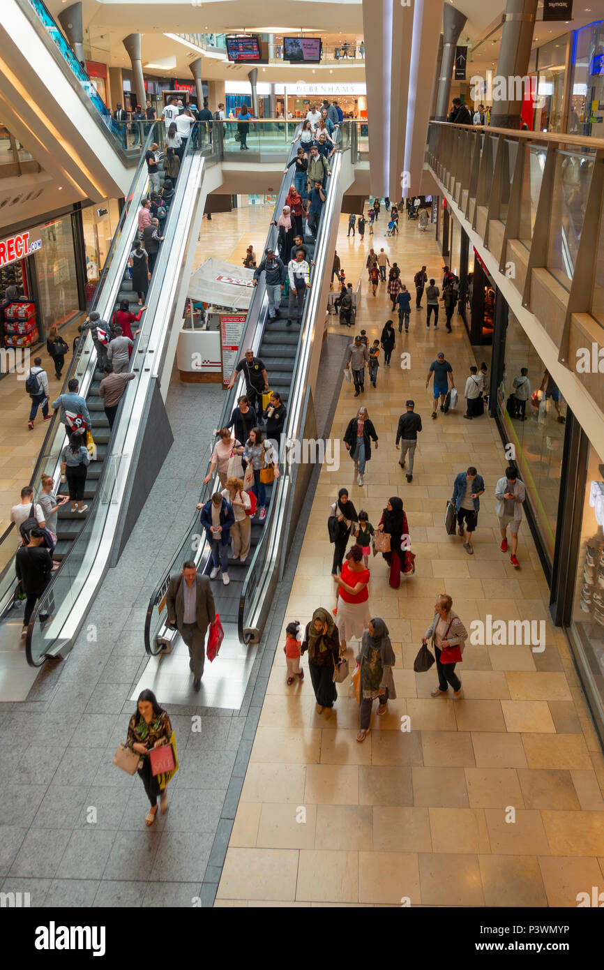 Shoppers sur et autour d'escaliers mécaniques dans le centre commercial Bullring, le centre-ville de Birmingham, England, UK. Motion Blur sur certaines personnes. Banque D'Images