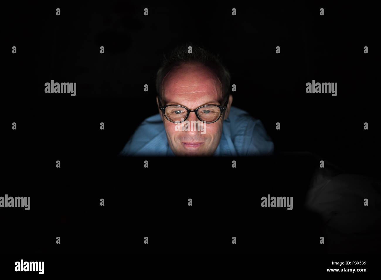 Scandinave mature man using digital tablet in dark room Banque D'Images