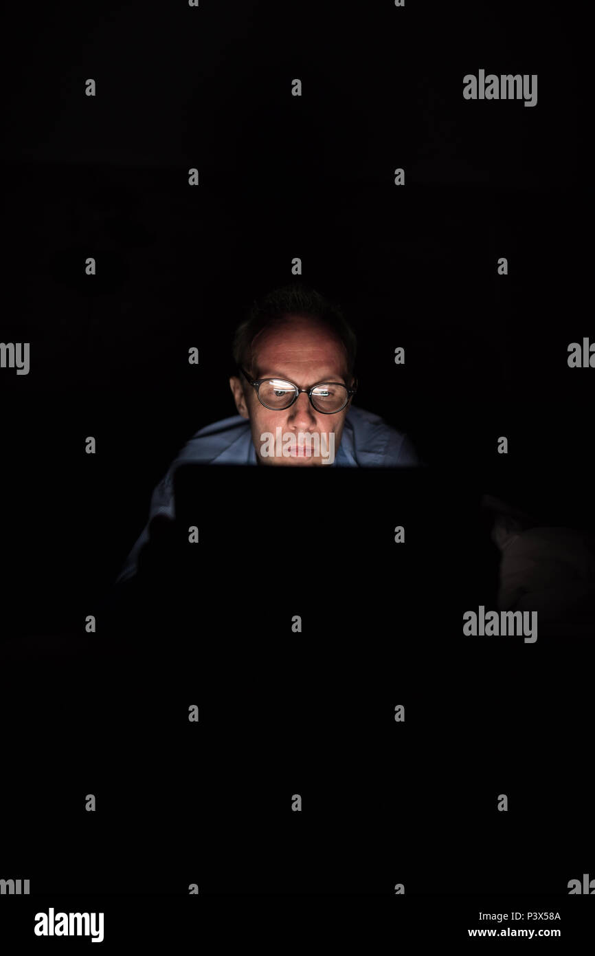 Scandinave mature man using digital tablet in dark room Banque D'Images