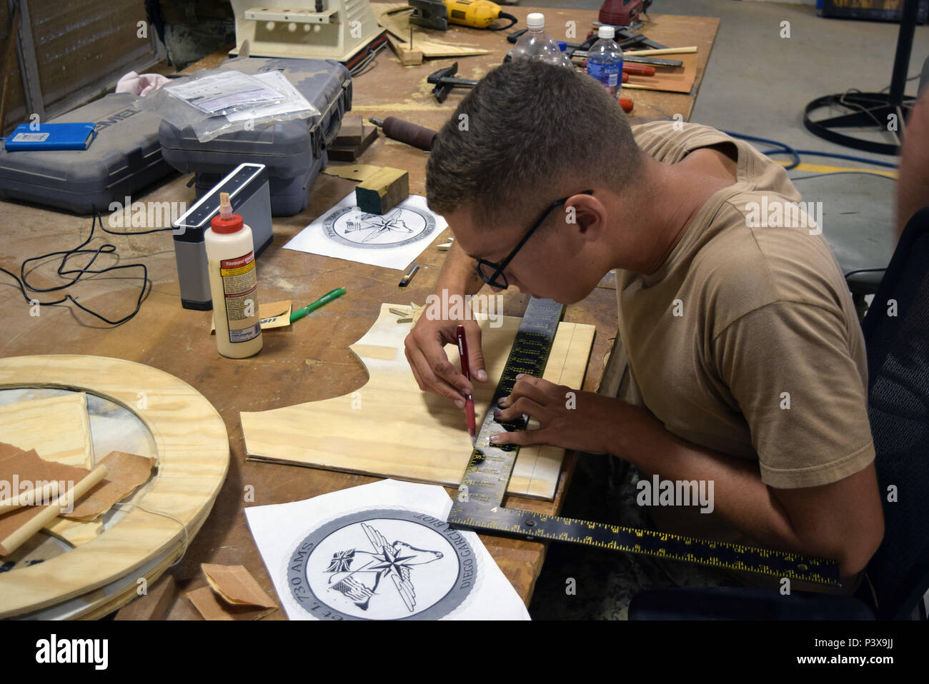 160727-N-OA861-259 DIEGO GARCIA (27 juillet 2016) - Builder Constructionman Heith Wright, affectés à la construction navale (bataillon Mobile NMCB), 4 points sur les mesures sur un morceau de contreplaqué pour une commande. Les mesures permettront de déterminer l'emplacement correct de la coupe et le placement du logo. (U.S. Photo par Marine Builder 2e classe Xavier Spencer/libérés) Banque D'Images