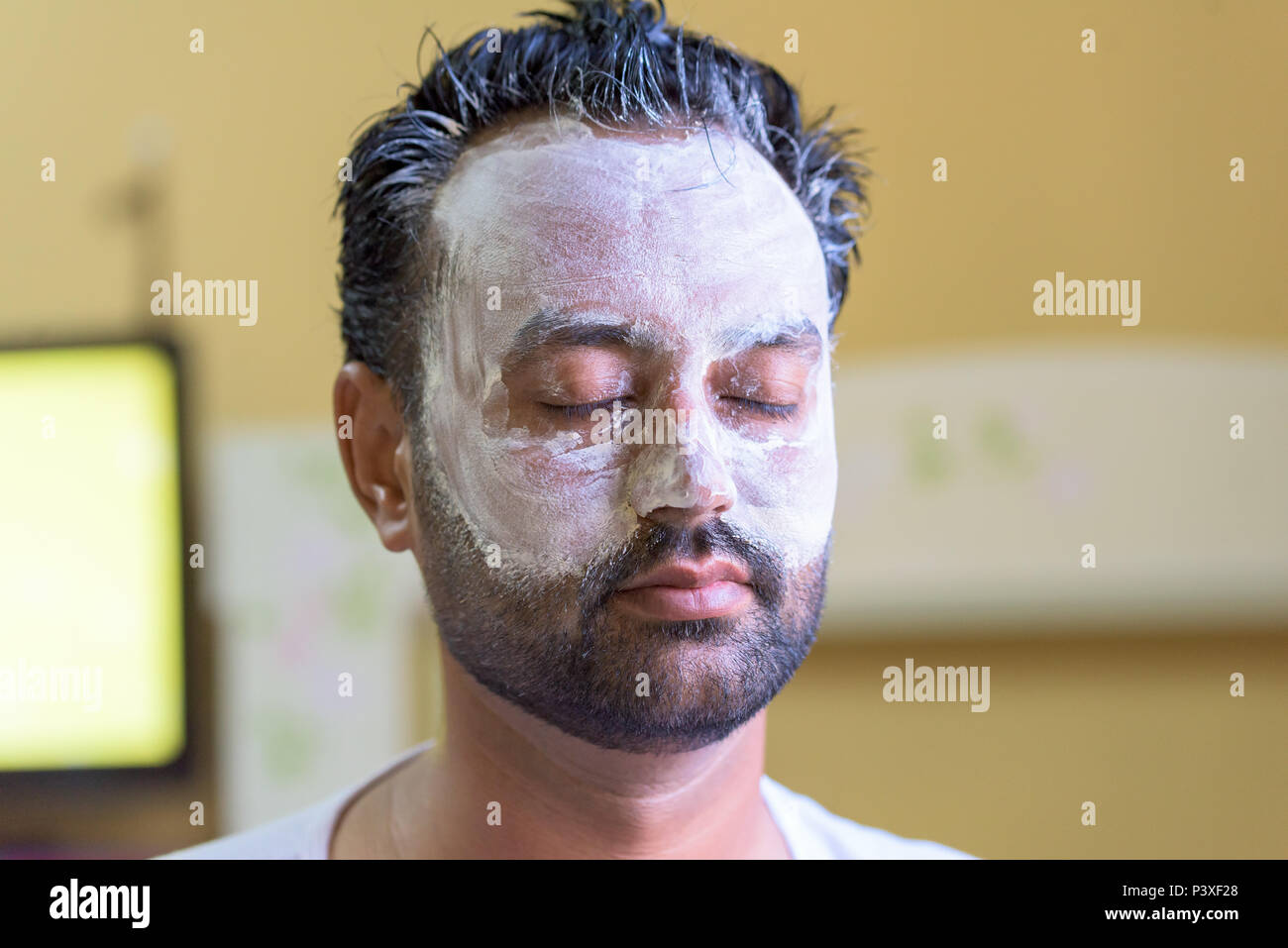 Yoing beared Homme portant un masque de beauté Banque D'Images