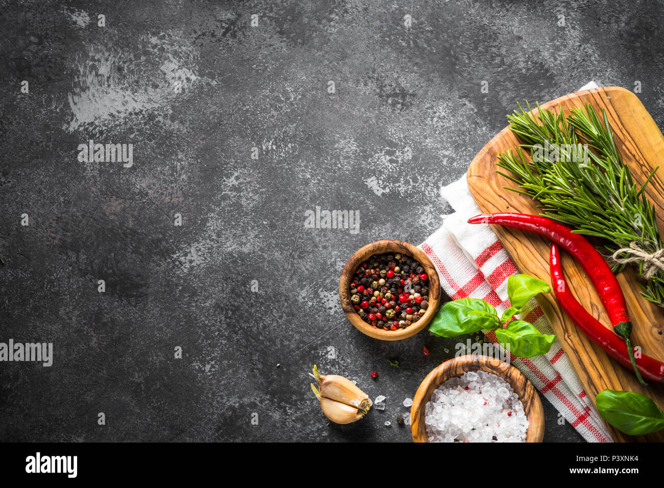 Épices, herbes et des ustensiles de cuisine sur la table en pierre noire. Arrière-plan de l'alimentation. Vue de dessus, copiez l'espace. Banque D'Images