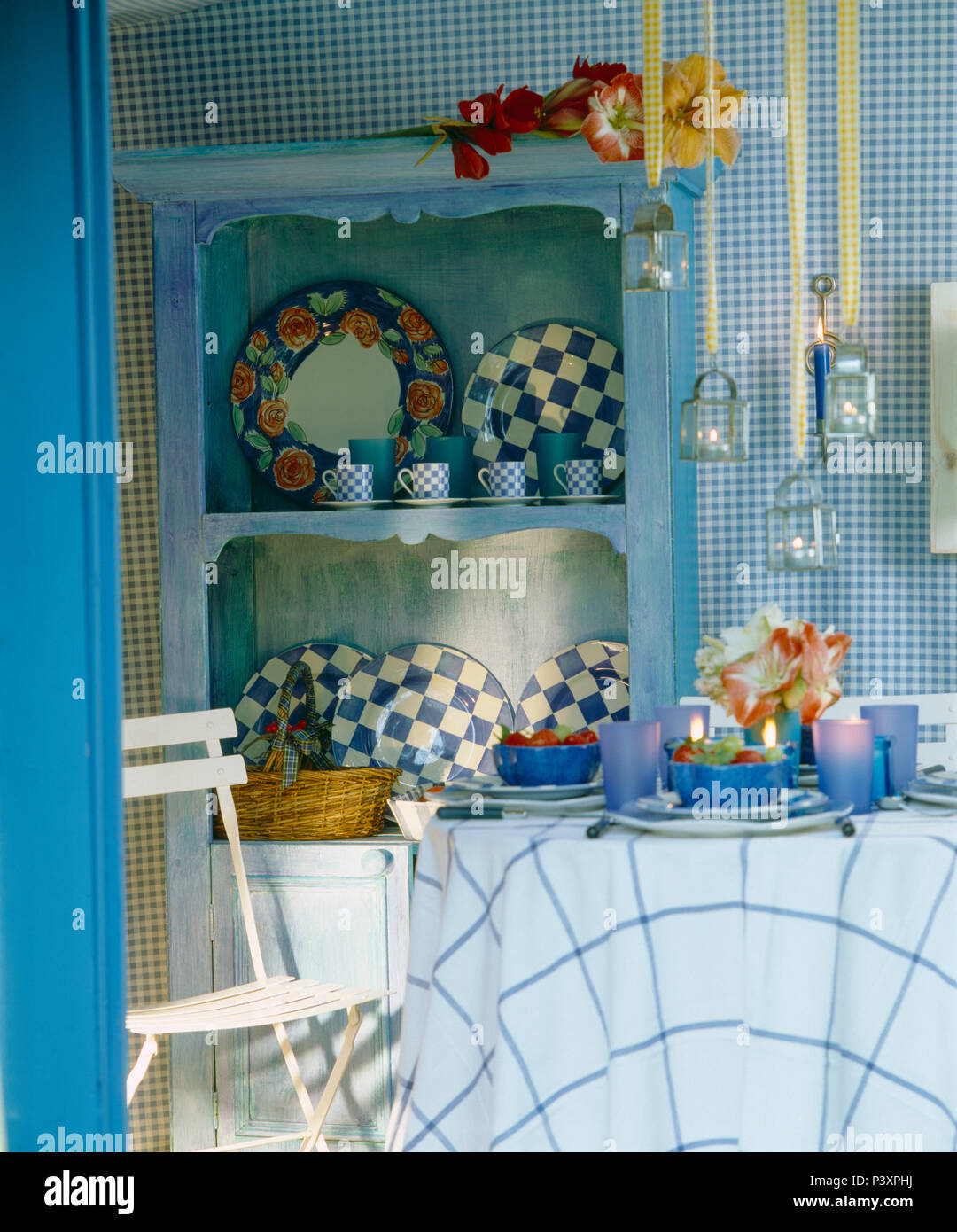 Tableau avec tissu de verre bleu et vérifiée et de la vaisselle dans la remise de jardin avec vu sur les plaques d'étagères bleu Banque D'Images