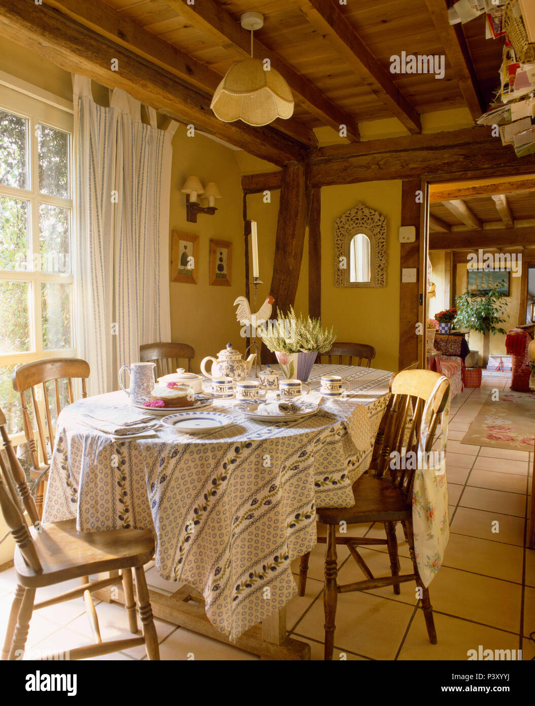 Tissu de coton blanc +bleu sur table set pour le thé en cottage salle à manger avec des chaises en bois ancien Banque D'Images