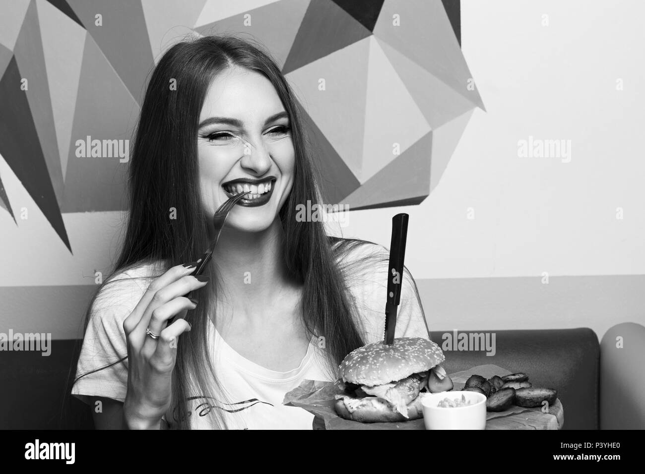 Laughing woman eating hamburger Banque D'Images